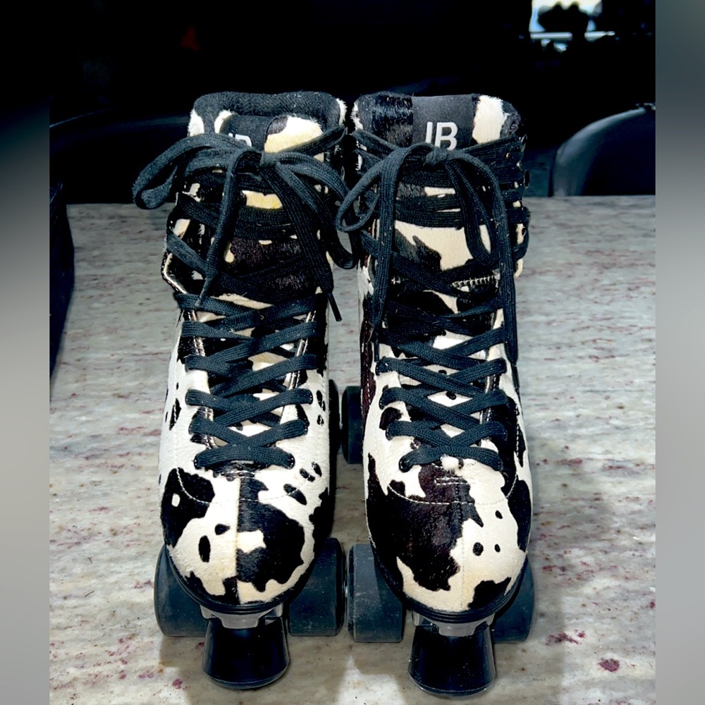 Cow print roller skates with pads for knee elbows and hands included.